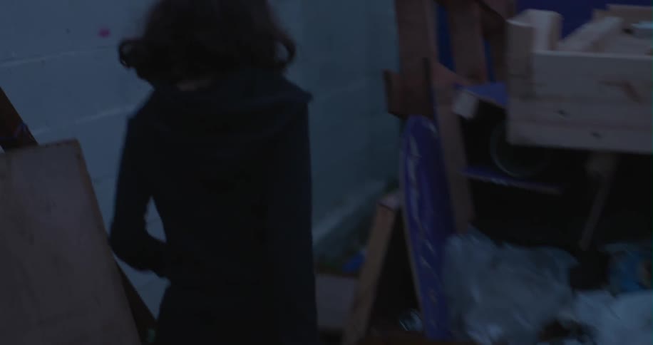 A woman walks down a dark alley