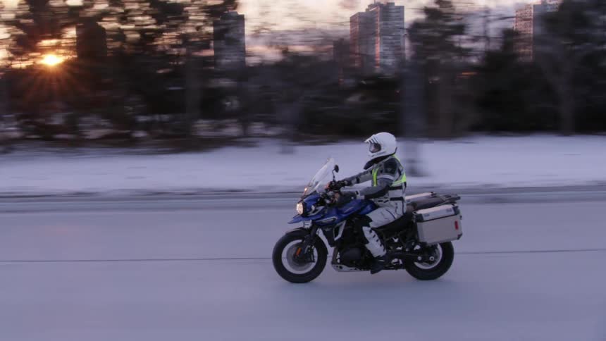 A man rides on a motorcycle near a city
