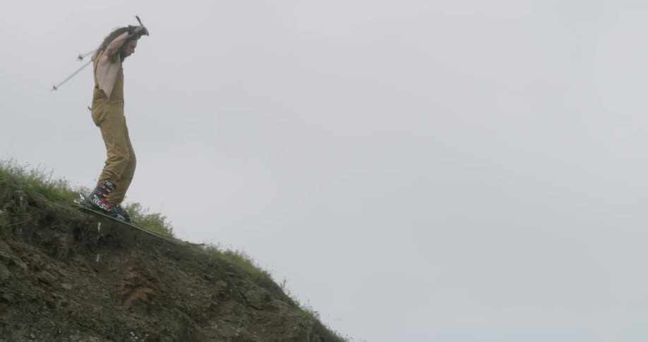 A man skis on grass off a cliff