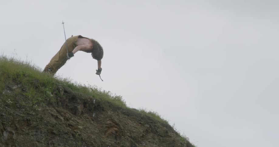 A man on skis flips off a cliff in the summer