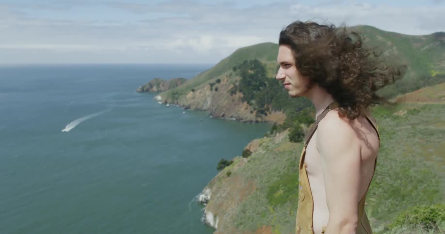 A man stands on a hilltop on a windy day