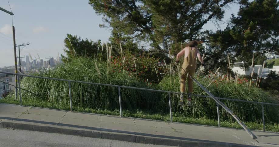 A man slides on skis across a railing on the side of the road