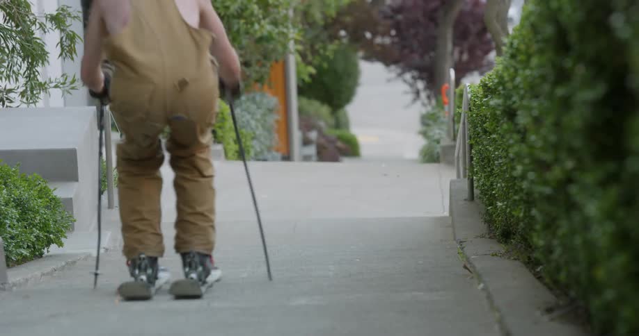 A man skis down a sidewalk and jumps the stairs