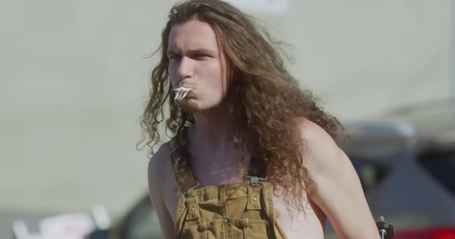 A man standing outside takes a bite out of a whole fish