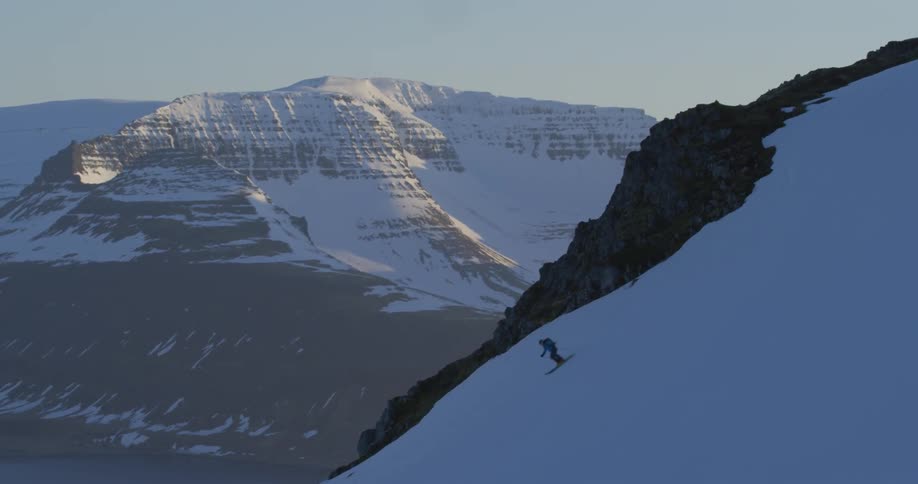 Person skiing down a steep snow covered mountain slope