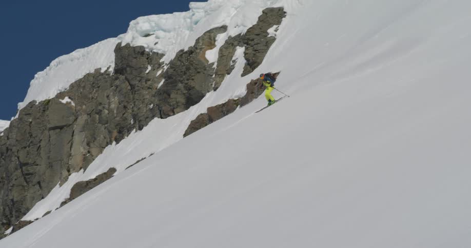 A person skis down a steep icelandic mountain slope in the spring