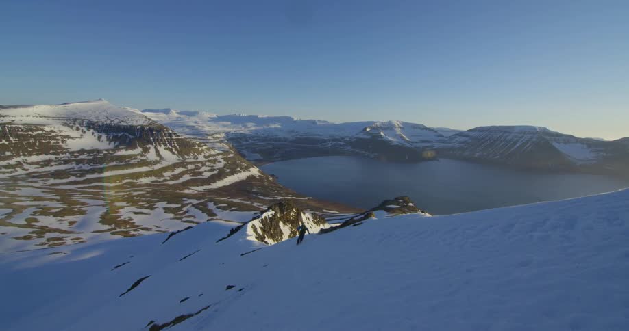 Person skiing down a snow covered mountain slope on sunny day