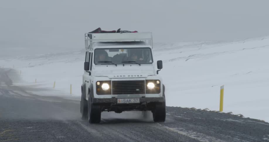 A land rover driving on a wet rural road in winter
