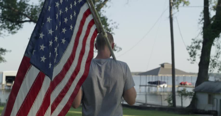 A man carries an american flag on a pole