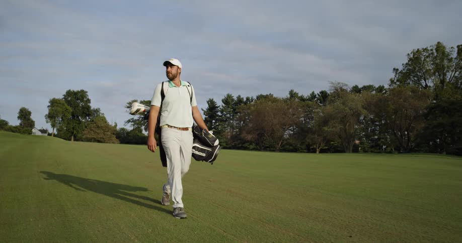 A man carries his golf bag while walking the course