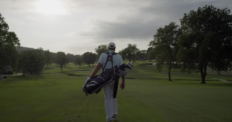 A golfer carries his clubs on the course