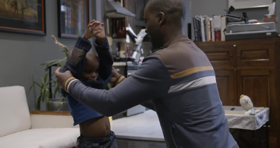 A child helps him pull his sweater off
