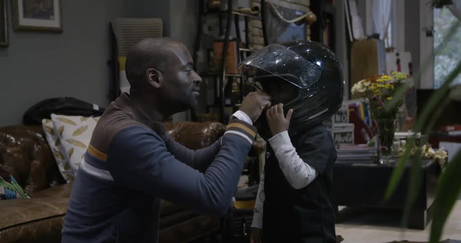 A man helps a young boy with a motorcycle helmet