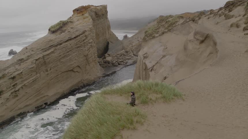 Person sits on the edge of a cliff looking out