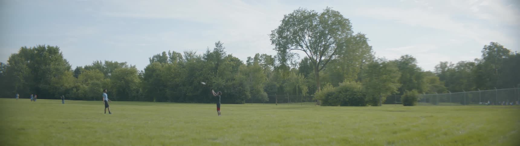 A teenage boy is throwing a football in a field on a cloudy day