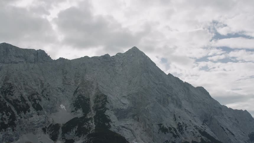The mountain covered in ice has clouds just touching the top