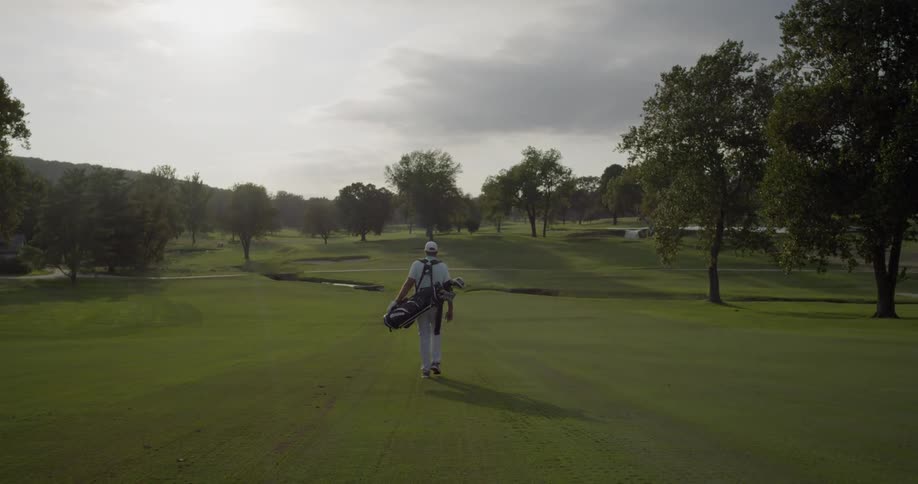 A man carries golf clubs on the course