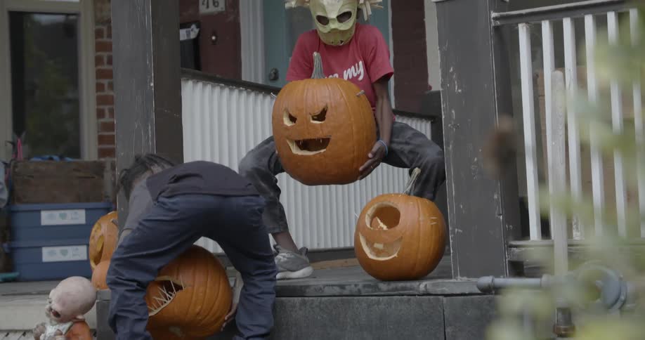 Young children pick up carved pumpkins