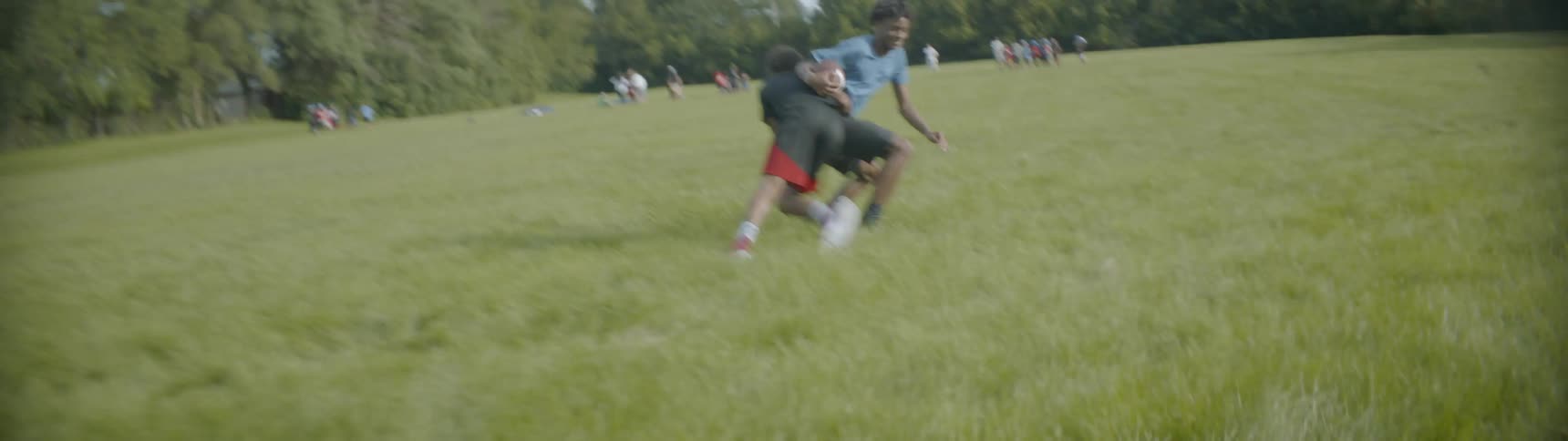 Two friends play football on a grass field