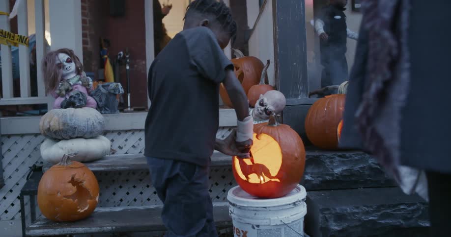 Child lights a pumpkin outside in the evening