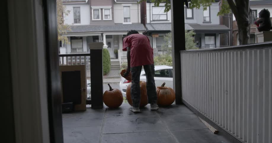 A young boy lifts the top off of a carved pumpkin