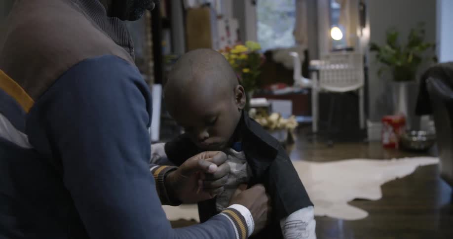 A parent helps his child dress