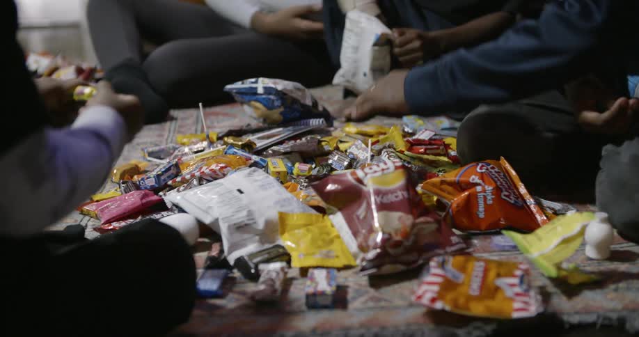Some kids are sitting around looking through a large pile of candy