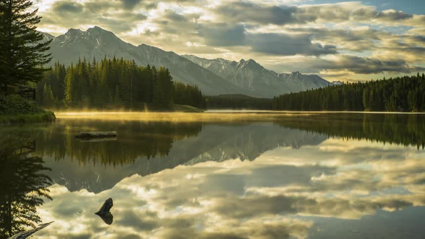 Fog rolls over a lake in a peculiar beautiful sunshine in Banff National Park