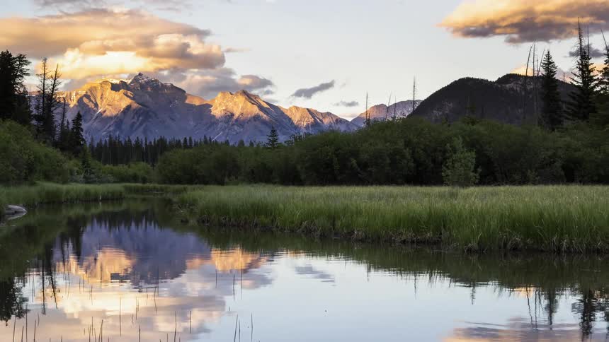 Scenic clouds and the Canadian Rockies reflect in the still Vermillion lake in Banff