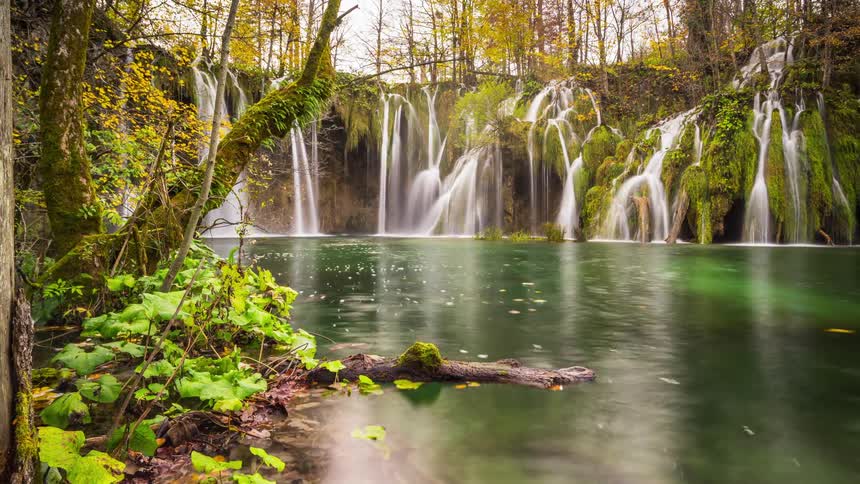 Plitvice waterfalls flow into a lake ringed by trees