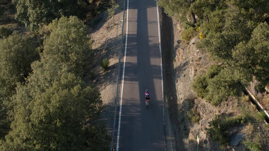 A person rides a bicycle on a mountain road on a sunny day in southern Spain