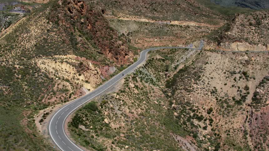 A person is riding their motorcycle down the long curvy road in the mountains of Southern Spain