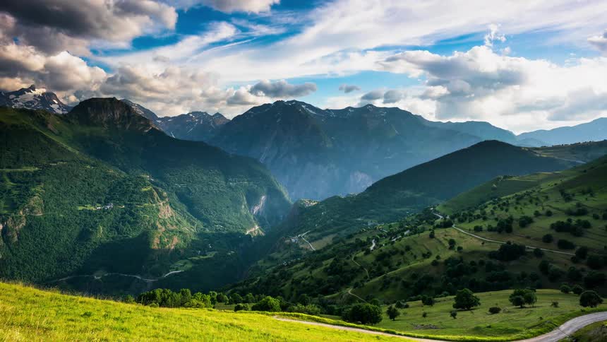 Clouds pass above an alpine valley surrounded by mountains