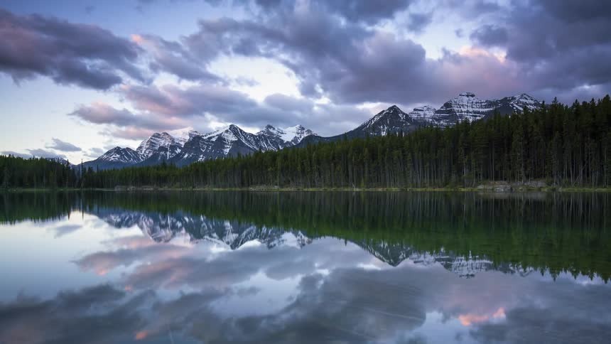 Time lapse of mountain and forest reflecting in a calm Herbert lake at sunrise in Banff, Canada