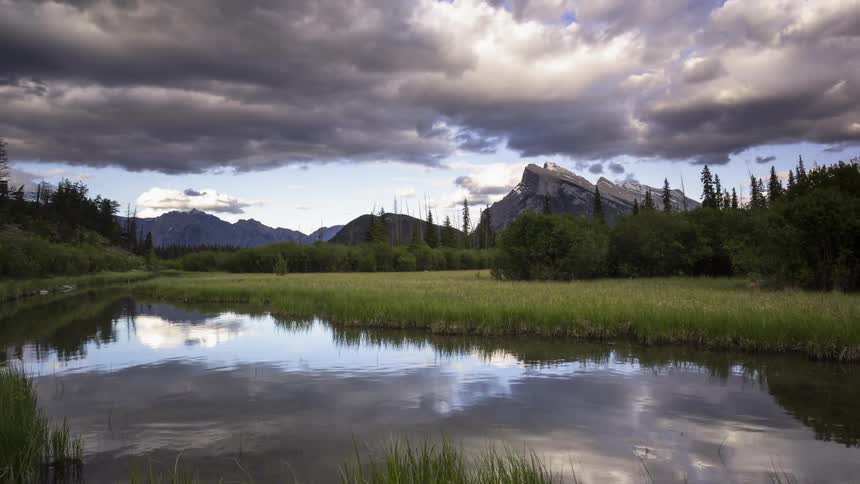 Colorful clouds pass over the Rockies reflecting in Vermilion lake in Banff