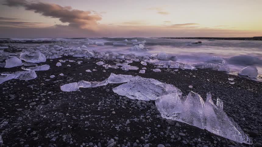 The waves crash against the shore filled with ice