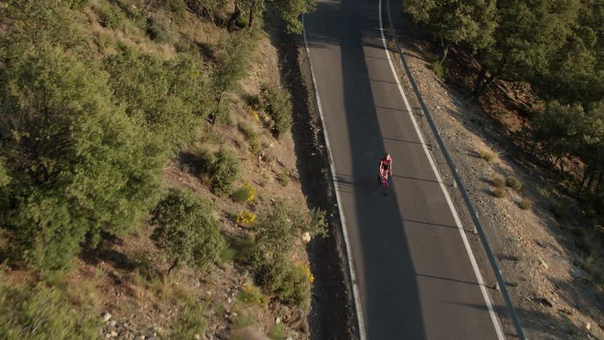 A bicyclist rides down a mountain road in rural Spain