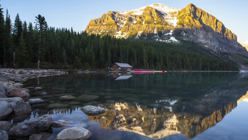 The sun rises over a cabin on the Lake Louise over scenic Rocky mountains in Banff, Canada
