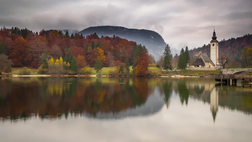 Water flows in the Bohinj lake near a church in Slovenia