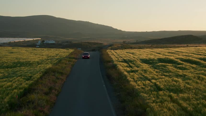 A car is travelling down a small country road in Spain