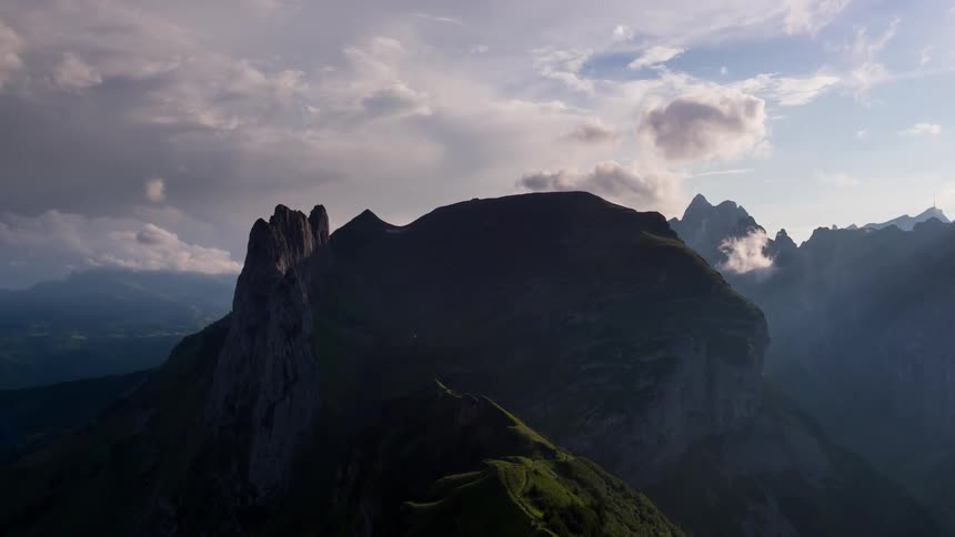 The tall mountain is shaded by the clouds