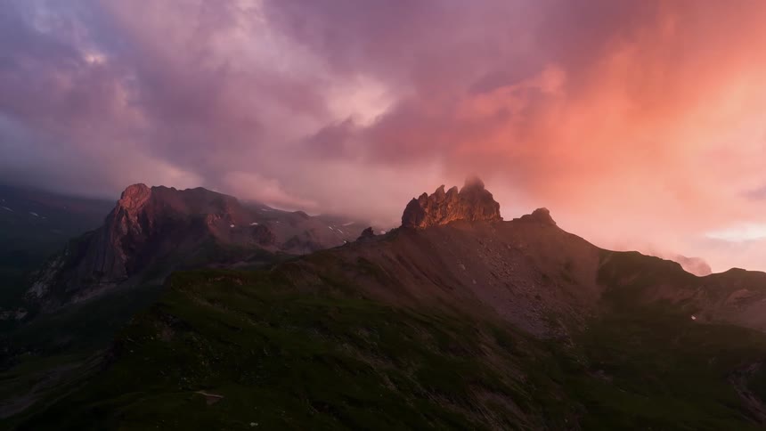 Gray and pink clouds hang above the tall mountains