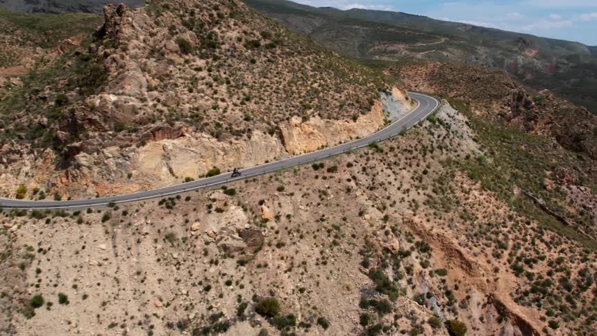 A biker rides down a mountain road in the dry Sierra Nevada mountain range