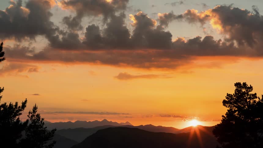 The sun sets below the mountains in a spectacular golden hour