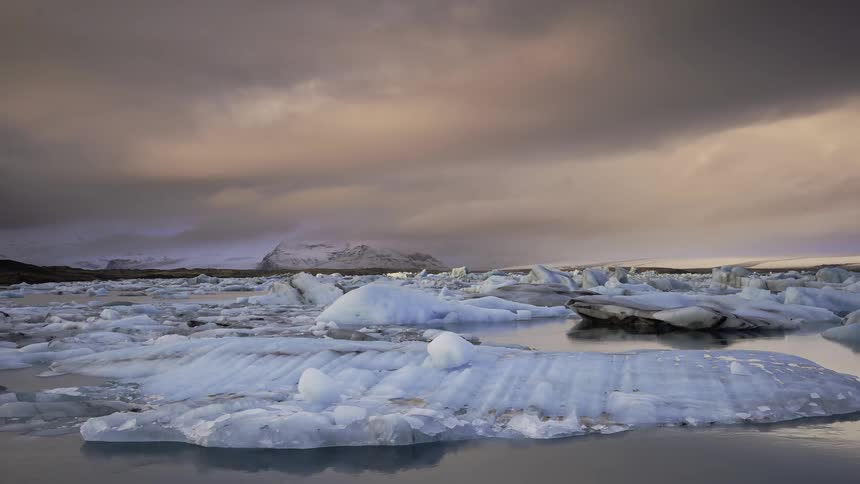 Storm clouds are drifting over icebergs through dawn