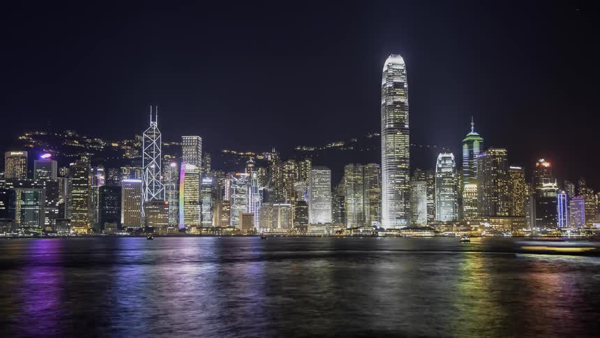 Boats travel on the water near the city at night