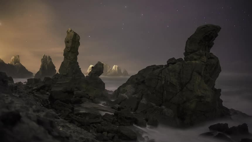 Time lapse of the ocean crashing against rocks at night