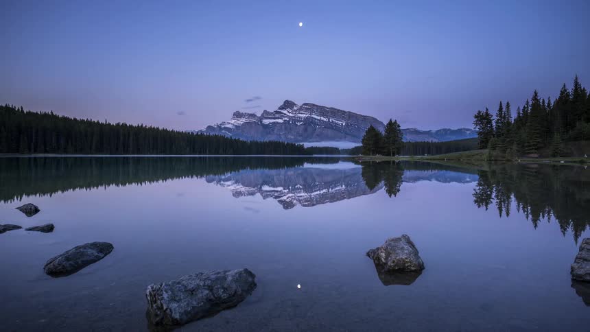 Time lapse of a calm lake as the sun rises over the Two Jack Lake in Banff National Park