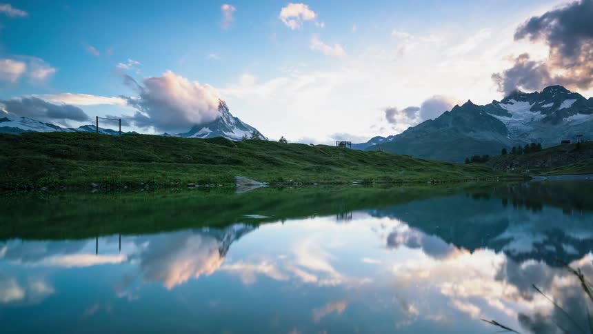 Clouds are reflecting in a mountain lake as time passes during the day