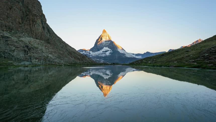 People hike while the sun rises over the Matterhorn